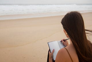 Woman writing on a beach