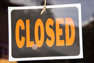 Closed sign hanging in business window by a string