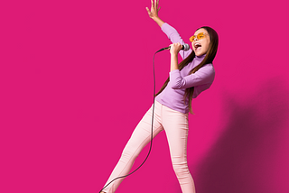 Woman using a microphone, striking an exuberant pose