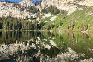 mountain and treescape being reflected in a lake