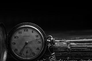A grayscale photo of a pocket watch lying on the ground.
