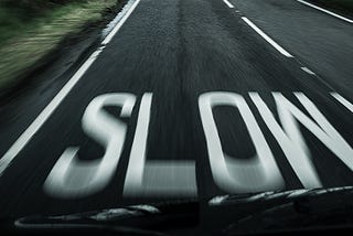 View from a fast-moving car, “slow” painted on road