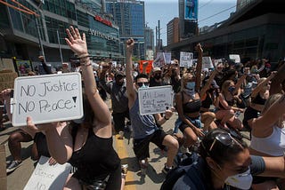 Group of BLM protestors kneel in Yonge and Dundas Square (Toronto, Canada).
