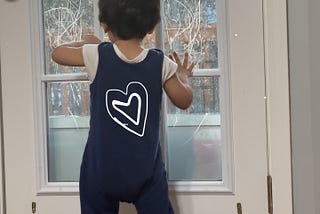 Image of my toddler scribbling with his crayons on the glass