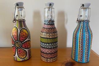 Three small glass bottles with intricate designs painted on them.