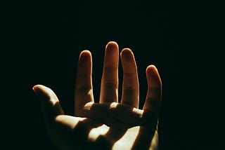 An open palm facing upwards with a dark and shadowy background.