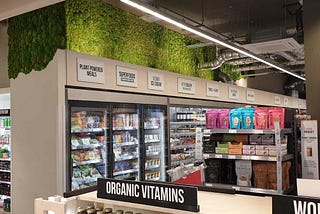 A retail store with a green wall above the cold drinks and frozen foods section