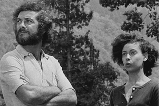 Screenshot from Éric Rohmer’s 1970 film Claire’s Knee. A man and a young woman stand surrounded by trees, looking off into the distance. The subtitle reads: It’s too beautiful. It’s all this beauty that exhausts me after a while.