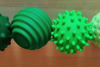 Four silicone-covered magnets in different shades of green, with different surface textures.