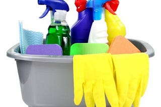 Cleaning bucket full of spray bottles, gloves and cleaning supplies.