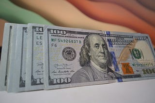 Hundred dollar bills standing next to each other. Photo by Blogging Guide on Unsplash