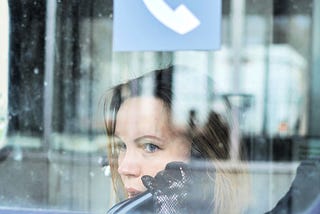 woman stares out of a window with reflective surfaces