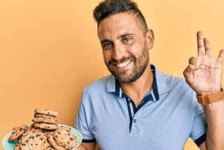 A man holding a plate of chocolate chip cookies. Courtesy of shuterstock.com / Krakenimages.com