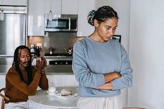 Two people are in a kitchen, facing away from each other