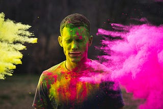 man’s face being covered in coloured powder outside
