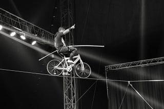 Un vélo en équilibre sur une corde avec un acrobate qui tente de ne pas tomber…