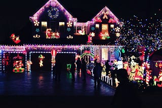 This is a picture of a two-story home decorated with lights and more for Christmas.