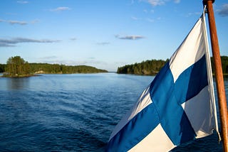 Finnish flag with idyllic lake Saimaa in the background
