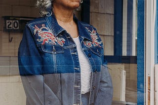 Portrait of Camille Givens, 69, looking through a glass door at her home in Kansas City.