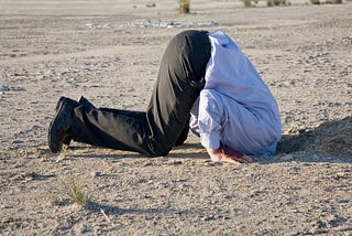 Man kneeling down with head buried in the Earth.