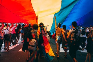 People underneath and holding up a pride flag.