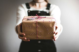 A woman holding out a wrapped gift