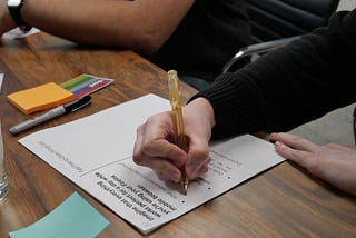 Image of a participant in a black long-sleeved shirt filling out a worksheet with an orange pen.