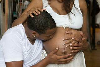pregnant couple. partner kissing pregnant belly