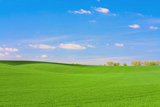 bright green field with blue sky and clouds