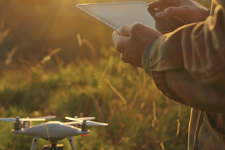 Picture of a drone and someone holding a tablet.