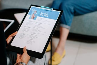 A woman holding a clipboard with her resume.
