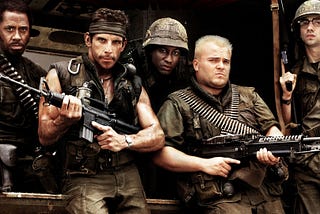 Tropic Thunder movie showing 5 actors dressed as army soldiers. All looking stern at the camera whilst holding weapons.