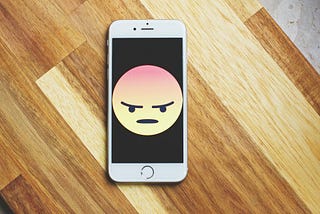 Phone screen with frowning emoji.