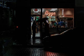 An outside view of a pizza restuarant at night,