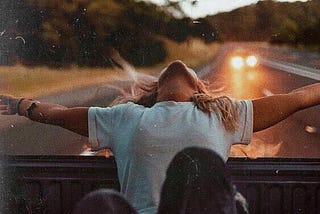 A girl leans out the back of a vehicle.