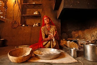 An Indian woman makes bread. Her shelves are at a low height, which is common in floor-sitting cultures.