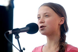 Activist Greta Thunberg speaking into a microphone as she leads the Youth Climate Strike.
