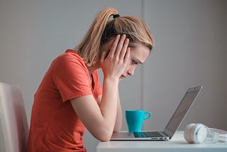 A woman with her head in her hands, staring at her laptop