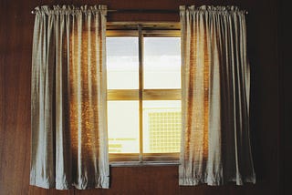 A closed window with curtains spread apart.