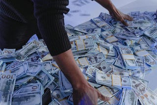 man bending over scattered bills, hands resting on the money