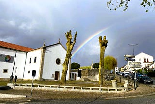 My town’s churchyard with a rainbow in the background agains the stormy dark skies.