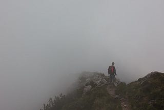 A person navigating a fogger mountain cliff, with uncertainty about what comes next