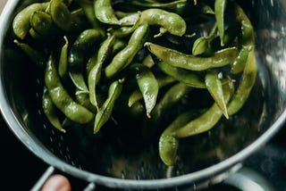 edamame being washed in a colander