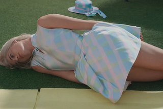 image from the Barbie movie where barbie (margot robbie) is lying on the ground looking hopeless