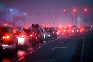 Traffic lights and a long queue of cars with their rear lights on contrast with the dim murky background. Buffalo, Niagara.