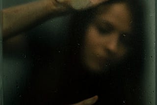 Image of a woman in a small space, apparently trapped behind glass