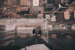 Feet standing on ledge overlooking city.