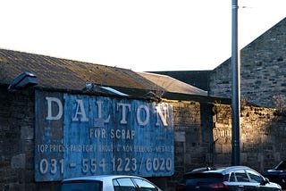Two cars in front of a sign that reads “Dalton – for scrap”