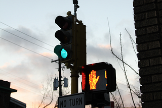 Image shows a lit stoplight that is green for cars, but red for pedestrians.