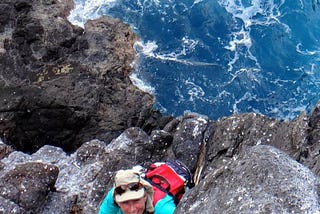 Rachel Rounds ascending rock cliff at Nihoa island